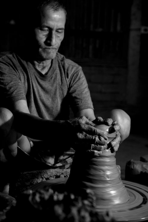 Free Artistic black and white photo of a potter shaping clay on a pottery wheel. Stock Photo