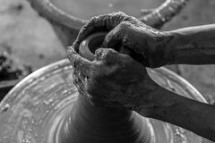 Black and white photo of hands molding clay on a spinning potter's wheel, showcasing artisanal craftsmanship.