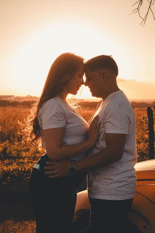 Free A couple shares a tender moment during sunset outdoors, creating a romantic silhouette. Stock Photo