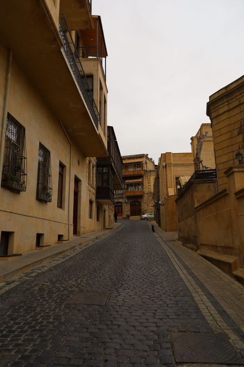 Free Charming narrow cobblestone street lined with historic buildings under overcast sky. Stock Photo