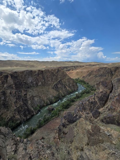 Free Beautiful canyon landscape with a river flowing through rugged terrain under a blue sky. Stock Photo