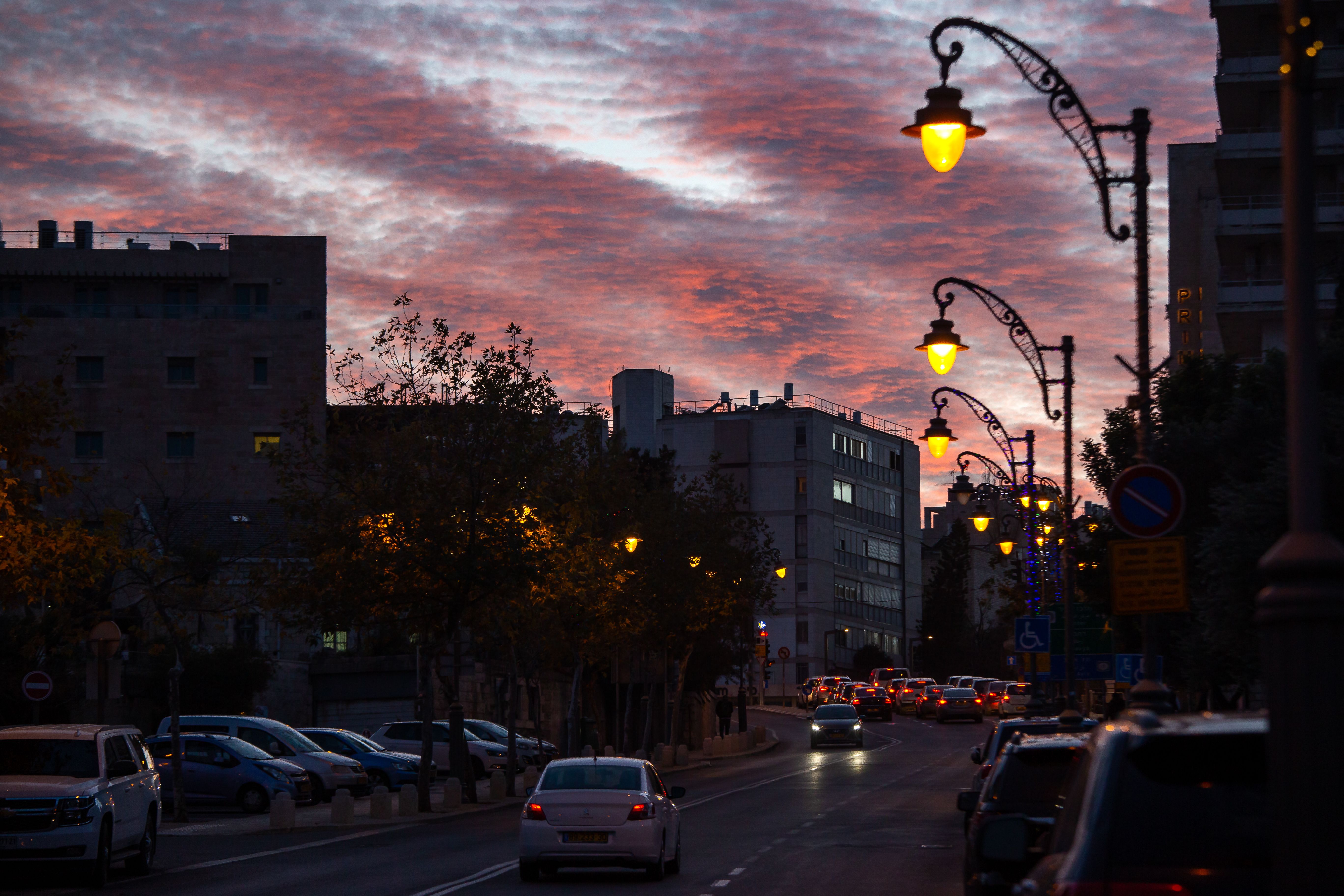 Captivating street view with vibrant sunset sky and illuminated streetlights, featuring silhouetted buildings.