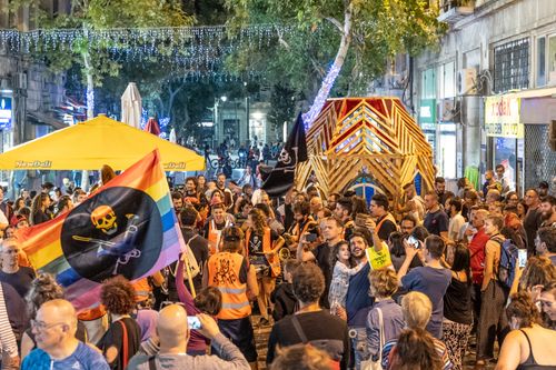 Free Crowd gathered for a lively street festival with flags and lights under a night sky. Stock Photo