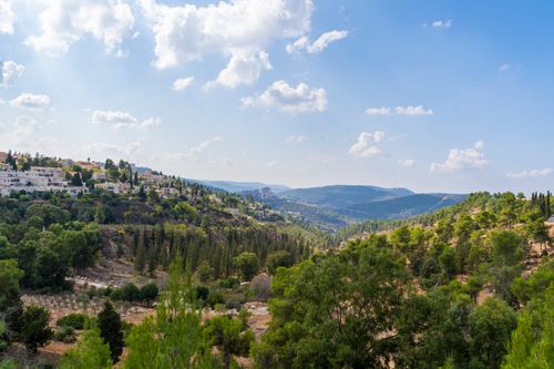 Free A breathtaking view of a green valley with distant hills under a bright blue sky with scattered clouds. Stock Photo