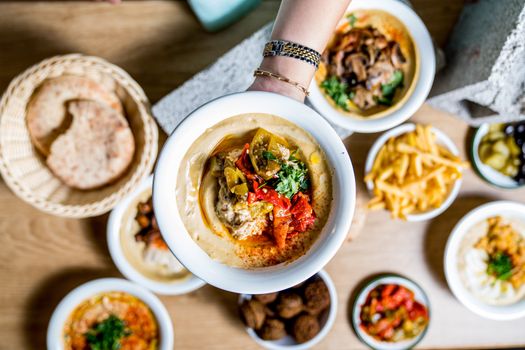 A vibrant array of Middle Eastern dishes including hummus, pita, and falafel presented on a wooden table.