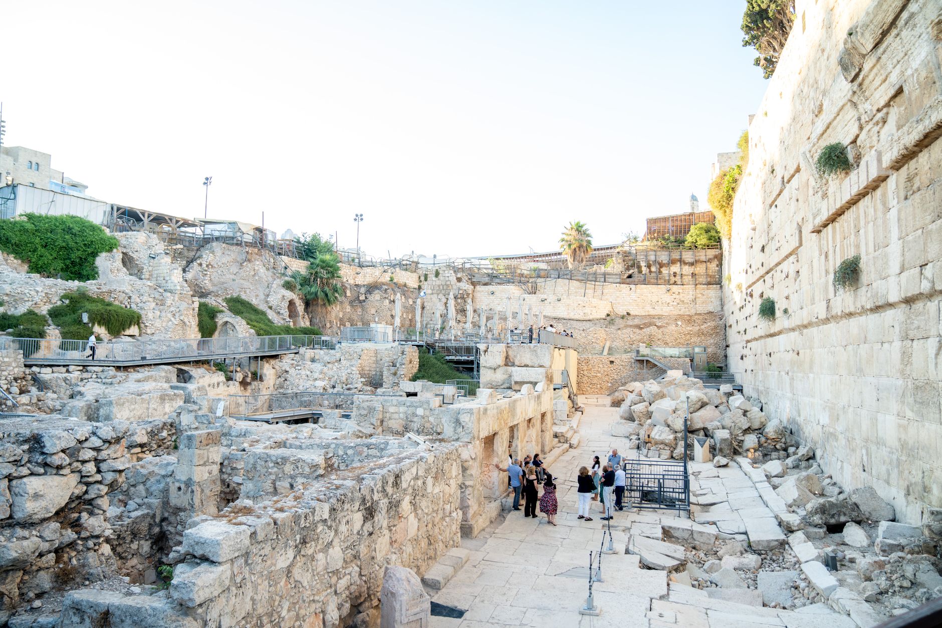 Tourists explore an ancient archaeological site in Jerusalem under bright daylight.