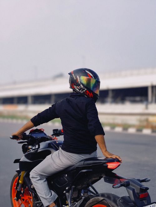 Free A motorcyclist wearing a helmet riding through an urban area on a clear day. Stock Photo