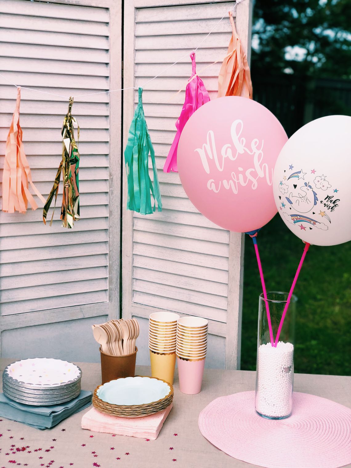 Colorful outdoor birthday table with balloons, garlands, plates, cups, and festive party supplies