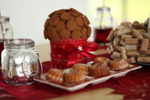 Composition of ginger cookies and sugar dusted muffins on plate with red Xmas decorations