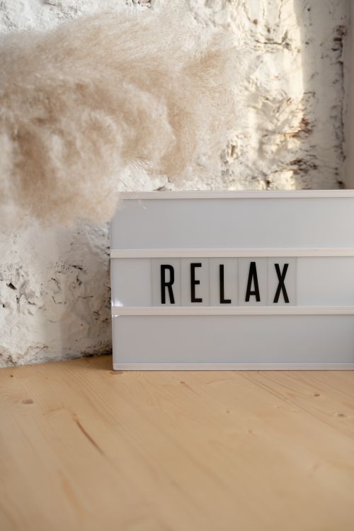 Free A minimalist sign displaying 'RELAX' with natural decor on a wood surface creates a soothing ambiance. Stock Photo