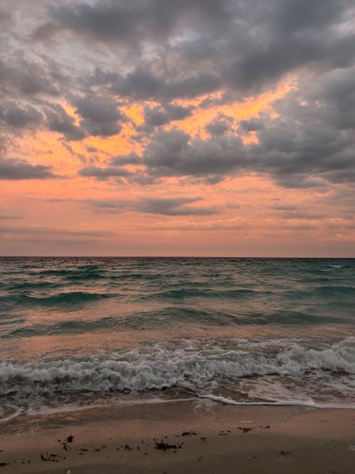Free A tranquil Cuban beach at sunset with rolling waves and a vibrant sky. Stock Photo