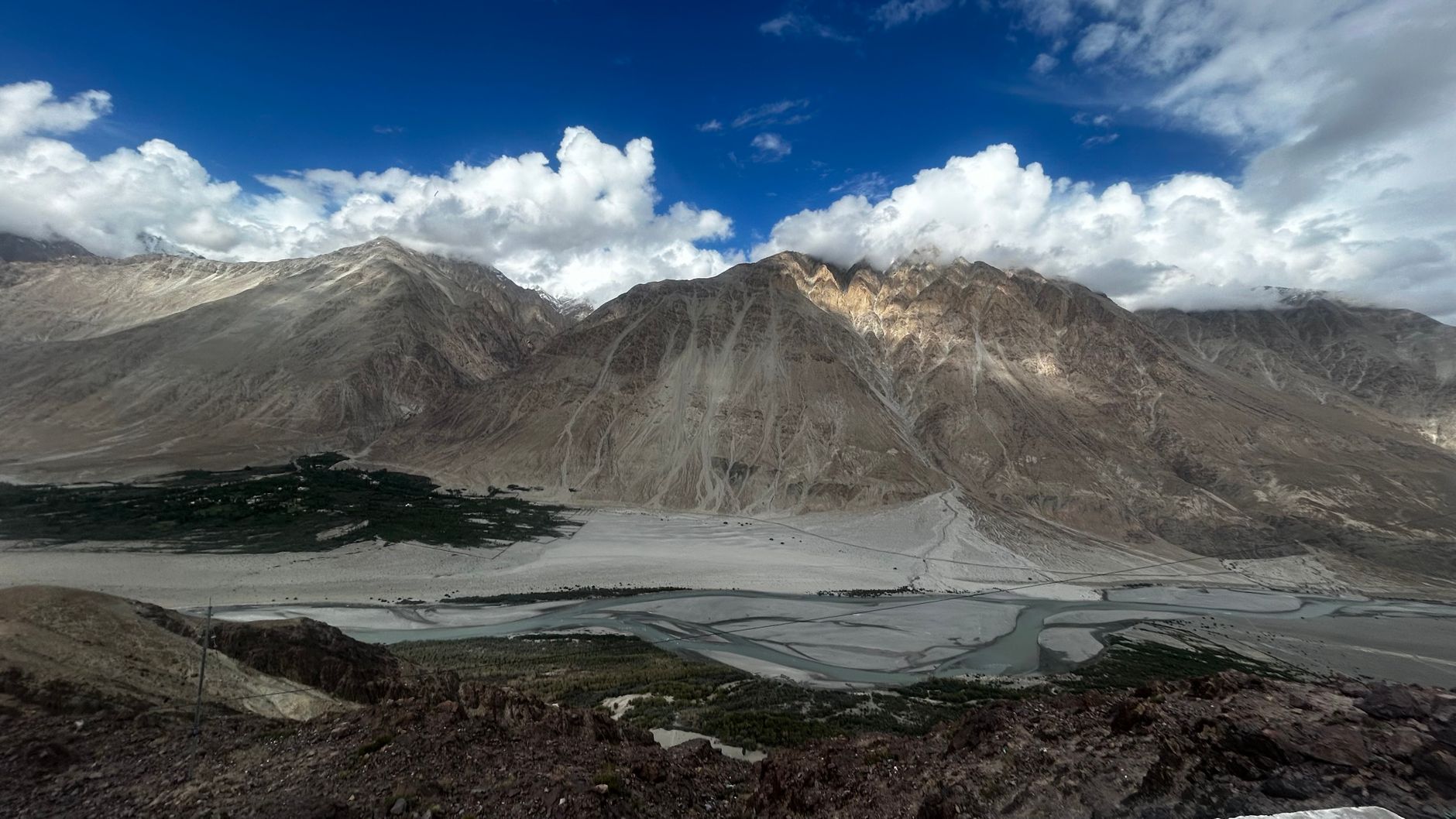 A breathtaking view of the majestic mountains and river in Nubra Valley, Ladakh, India, under a vibrant blue sky.