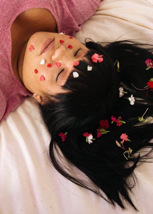 Free Tender plus size ethnic female with petals on face Stock Photo