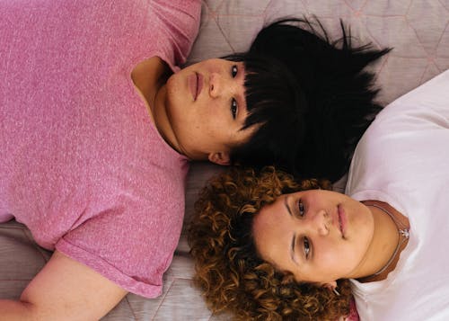 Dreamy girlfriends lying together on bed