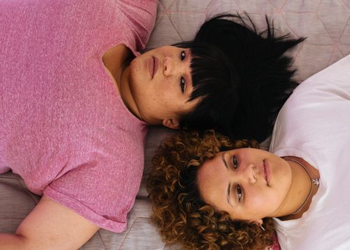 Free Top view of multiethnic female friends lying on bed while one woman looking at camera Stock Photo
