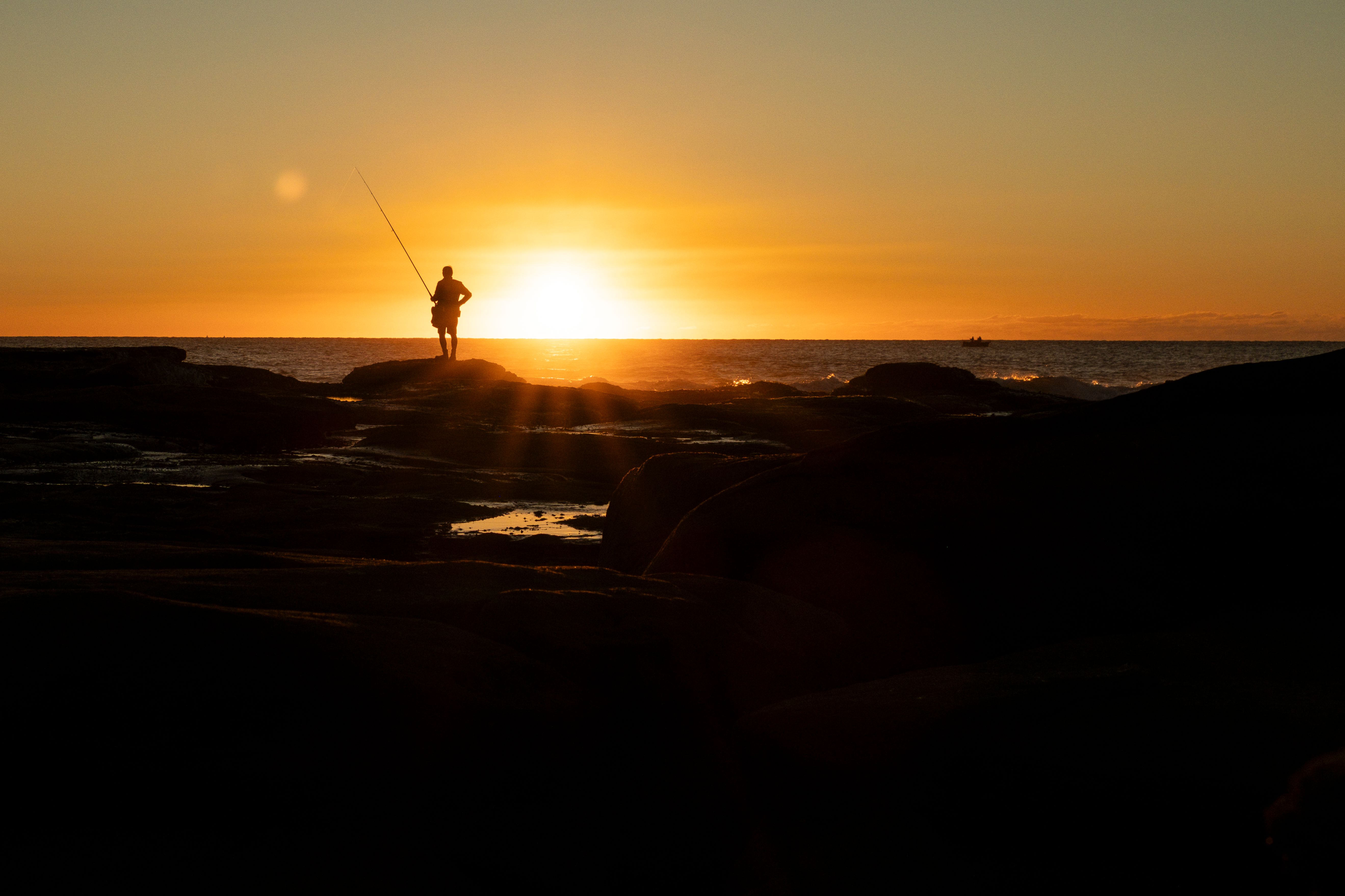 A lone angler casting at dawn while working reef country in calm coastal water.