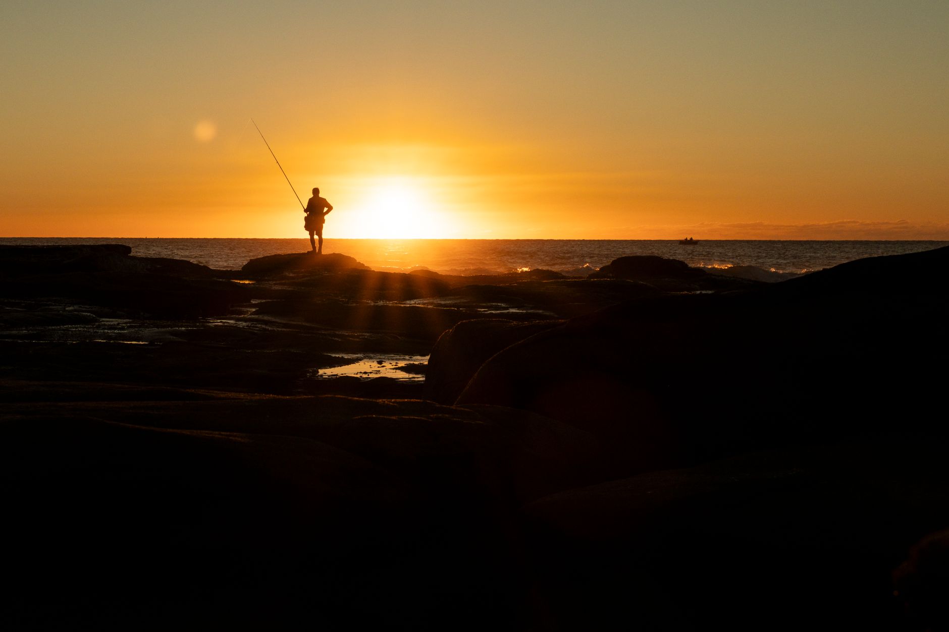 A lone angler casting at dawn while working reef country in calm coastal water.