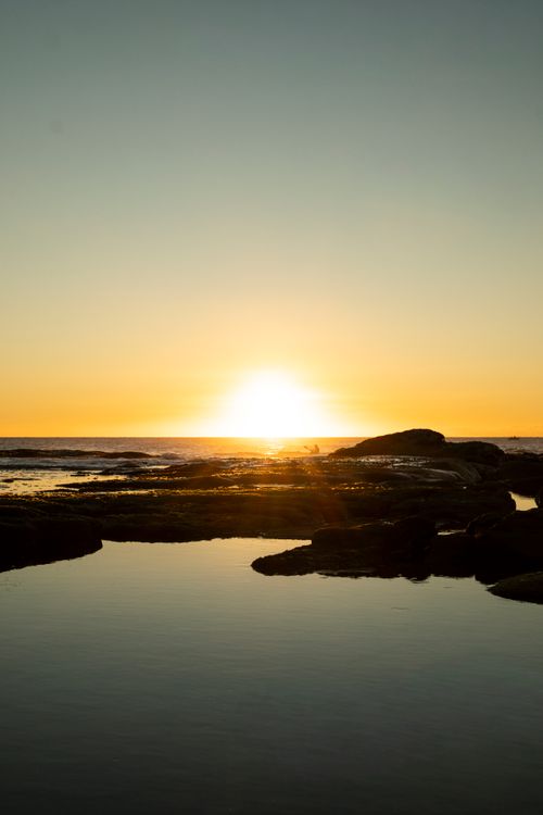 Free Serene sunrise over rocky shore with still waters on Sunshine Coast, Queensland, Australia. Stock Photo