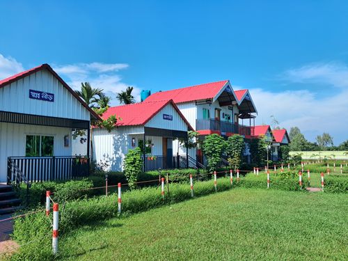 Free Picturesque cottages with red roofs surrounded by greenery under a bright blue sky. Stock Photo