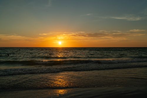 Free Serene beach sunset with golden hues and gentle waves on the shoreline. Stock Photo