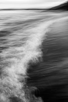 Monochrome image capturing the dynamic motion of waves on Scotland's coast.