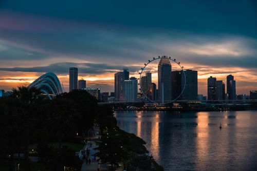 Free A beautiful sunset view of Singapore's skyline and Ferris wheel reflecting on the water. Stock Photo
