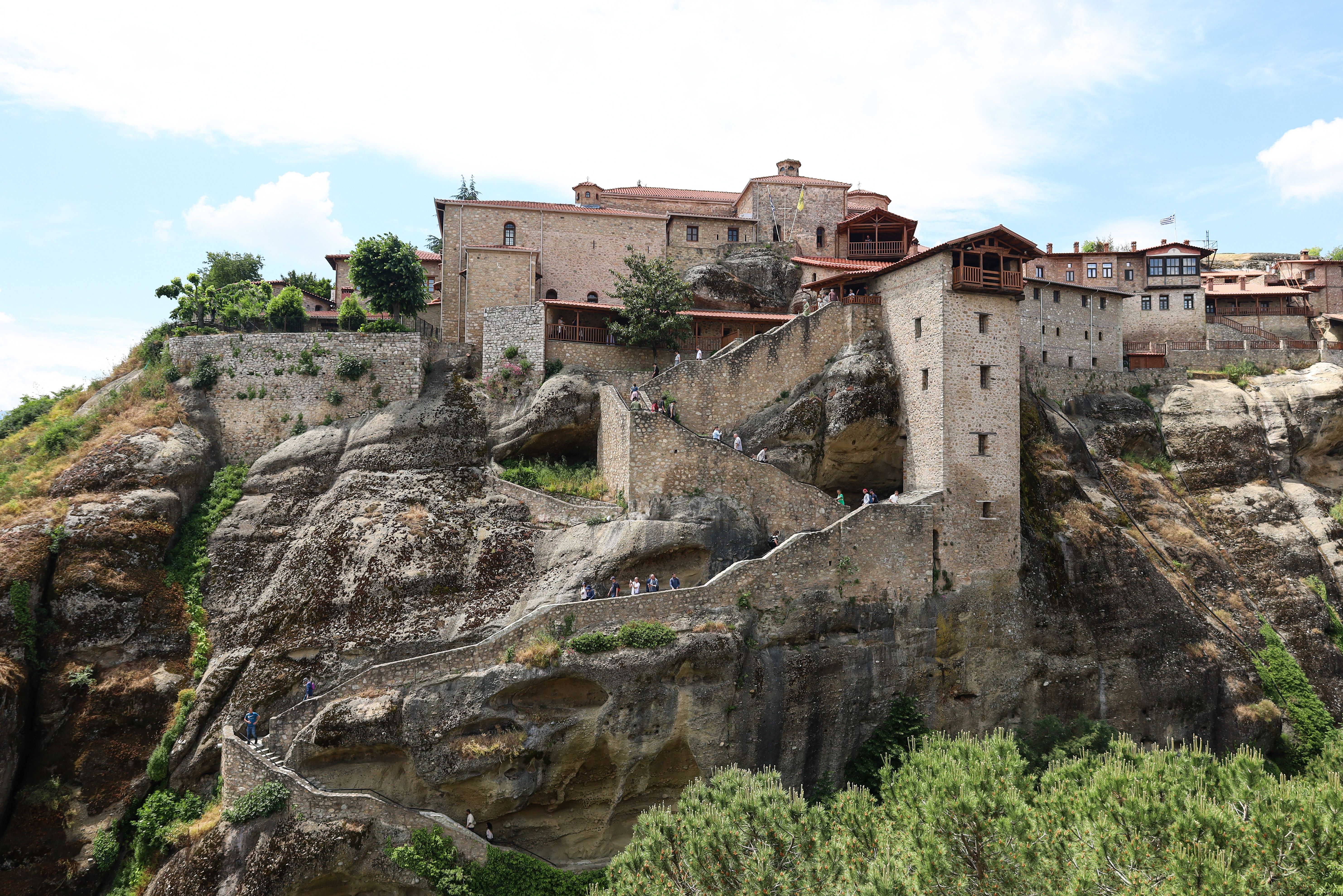 Panoramic view of Meteora monasteries perched atop rocky cliffs in Greece, showcasing stunning architecture and natural landscape.
