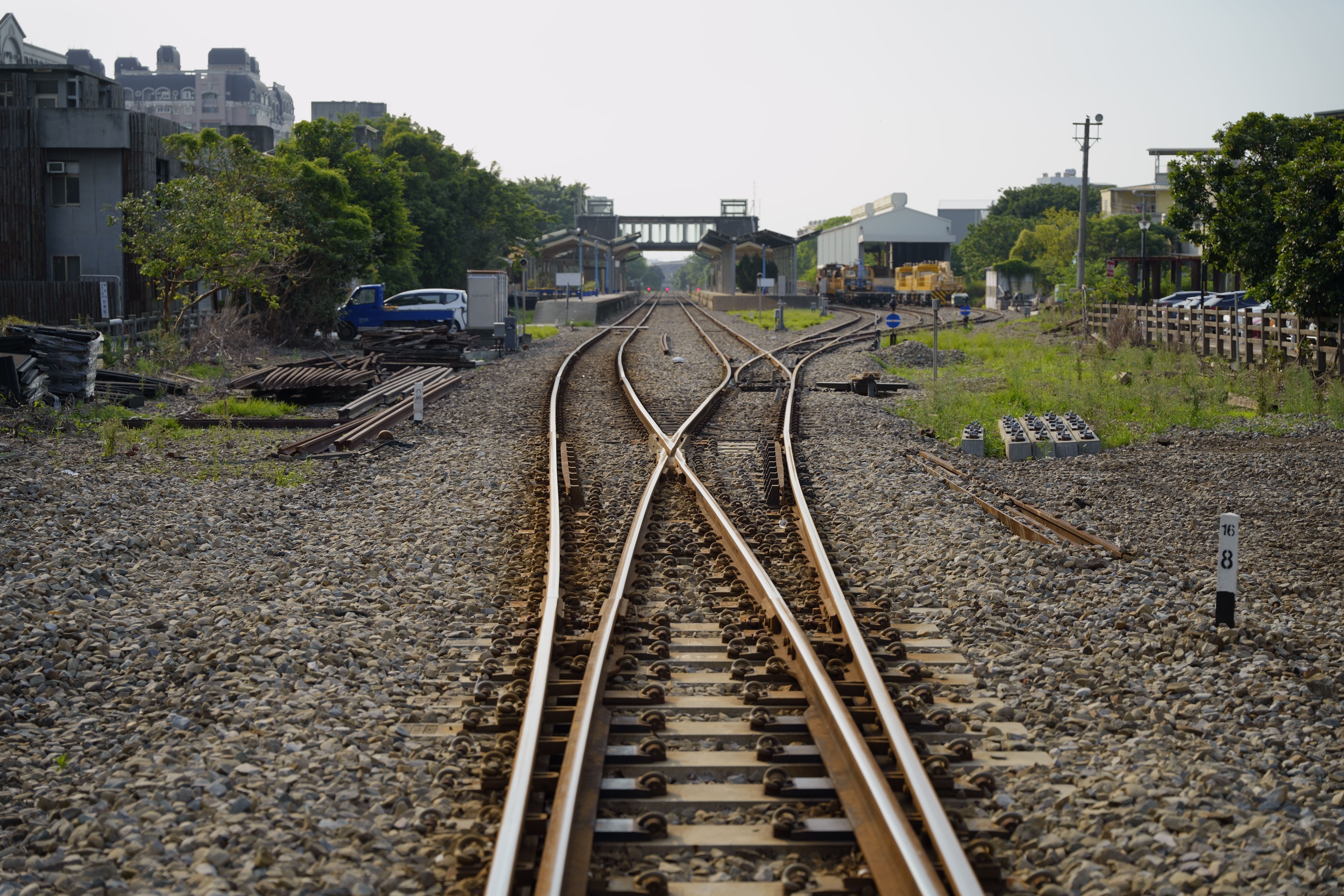 Converging railway tracks in Hsinchu County, Taiwan, showing industrial surroundings and clear skies.
