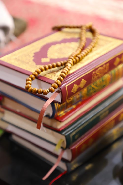Free A stack of colorful religious books with wooden prayer beads on top, creating a spiritual ambiance. Stock Photo