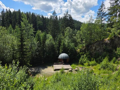 Free A serene forest scene featuring a unique wooden cabin under a bright blue sky. Stock Photo