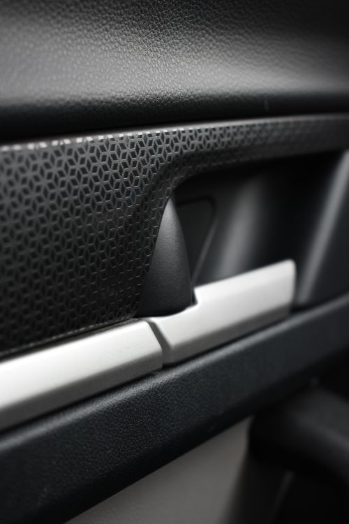 Free Detailed view of a car door handle featuring a textured dark surface and sleek lines. Stock Photo