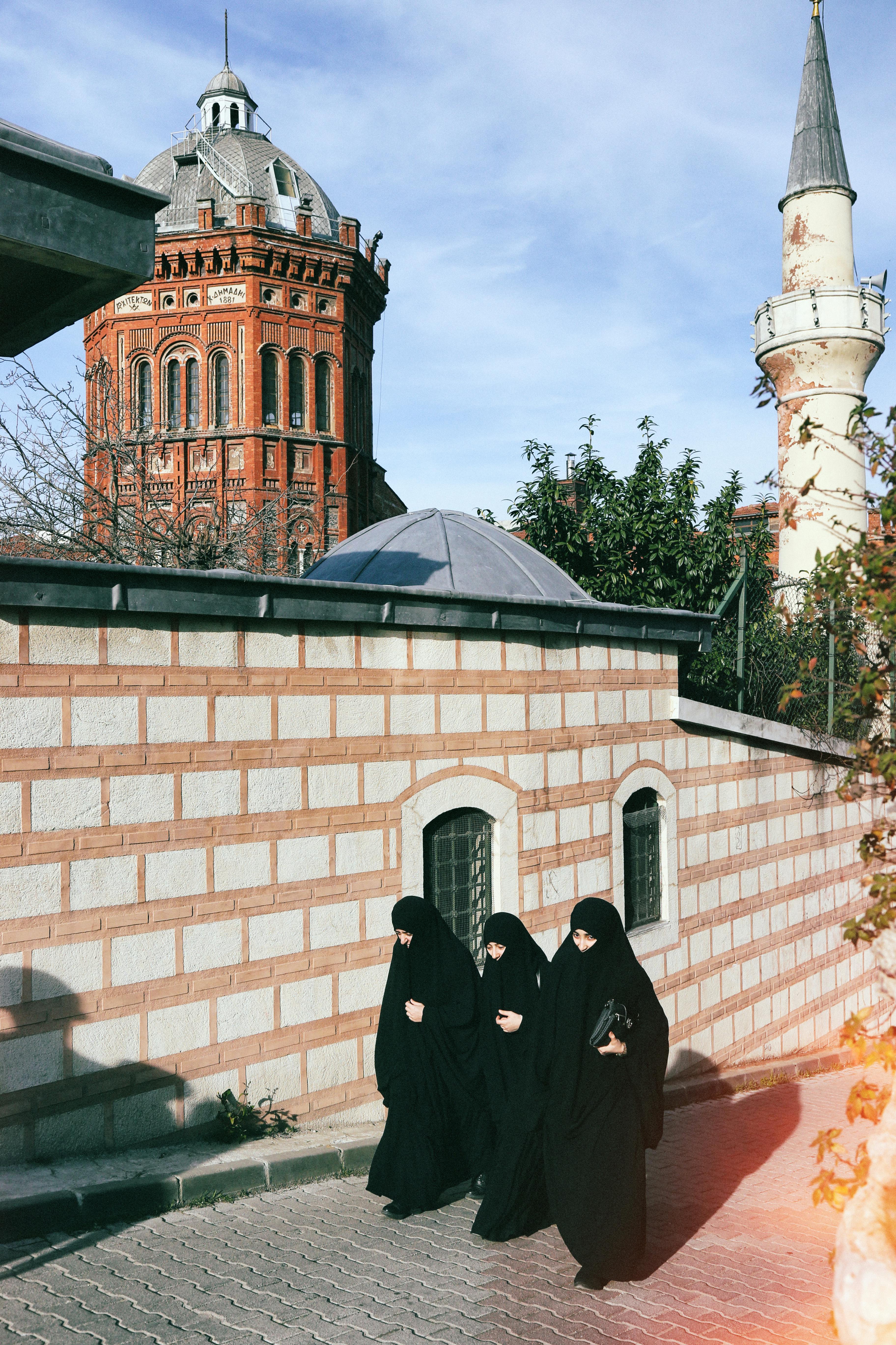 Women in traditional attire walking by historic architecture in Fatih, Istanbul.