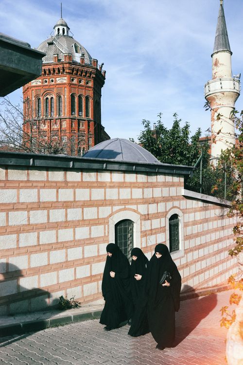 Free Women in traditional attire walking by historic architecture in Fatih, Istanbul. Stock Photo