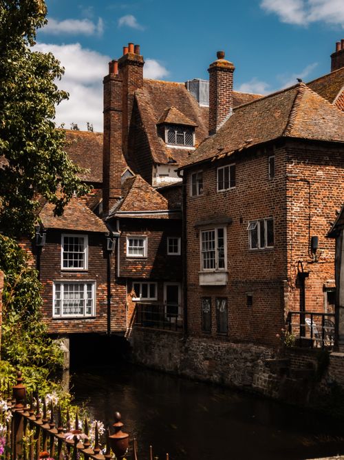 Free Charming historic brick buildings line a tranquil river in Canterbury, UK. Stock Photo