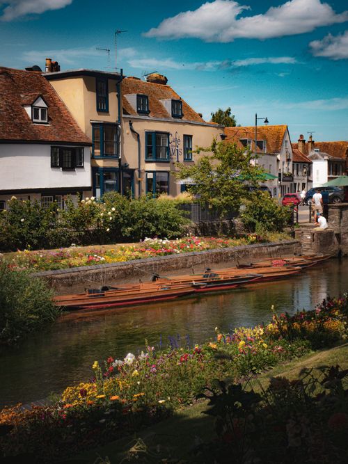 Free Picturesque riverside scene in Canterbury with colorful flowers and historic buildings. Stock Photo