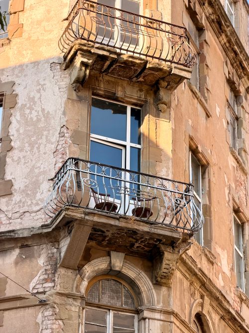 Free A charming old balcony with wrought iron railing on a historic building, exuding European architectural charm. Stock Photo