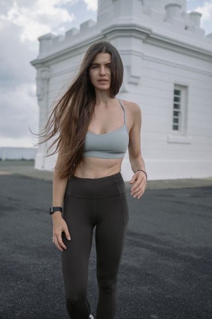 Woman exercising outdoors near a historic building, showcasing fitness and lifestyle.