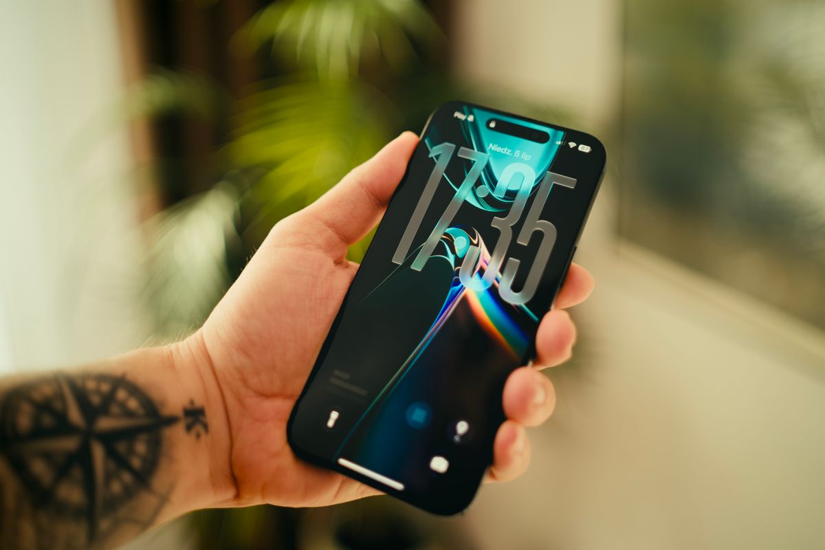 Bir kişi akıllı telefonu eliyle tutuyor, ekranda renkli bir oyun sahnesi var