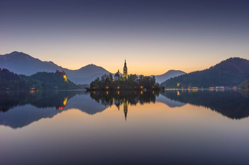 Free Peaceful sunrise over Lake Bled in Slovenia, reflecting the surrounding mountains and church. Stock Photo