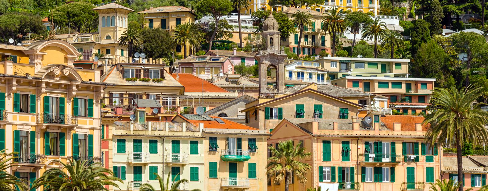 Colorful hillside architecture and palm trees in Santa Margherita, Italy, displaying vibrant coastal charm.