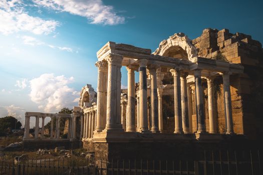 Explore the ancient Roman ruins showing majestic columns and arches under a warm sunset sky.