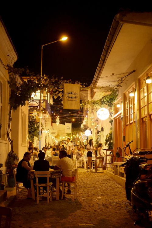 Free People enjoying a vibrant evening in a narrow, illuminated Mediterranean alley. Stock Photo