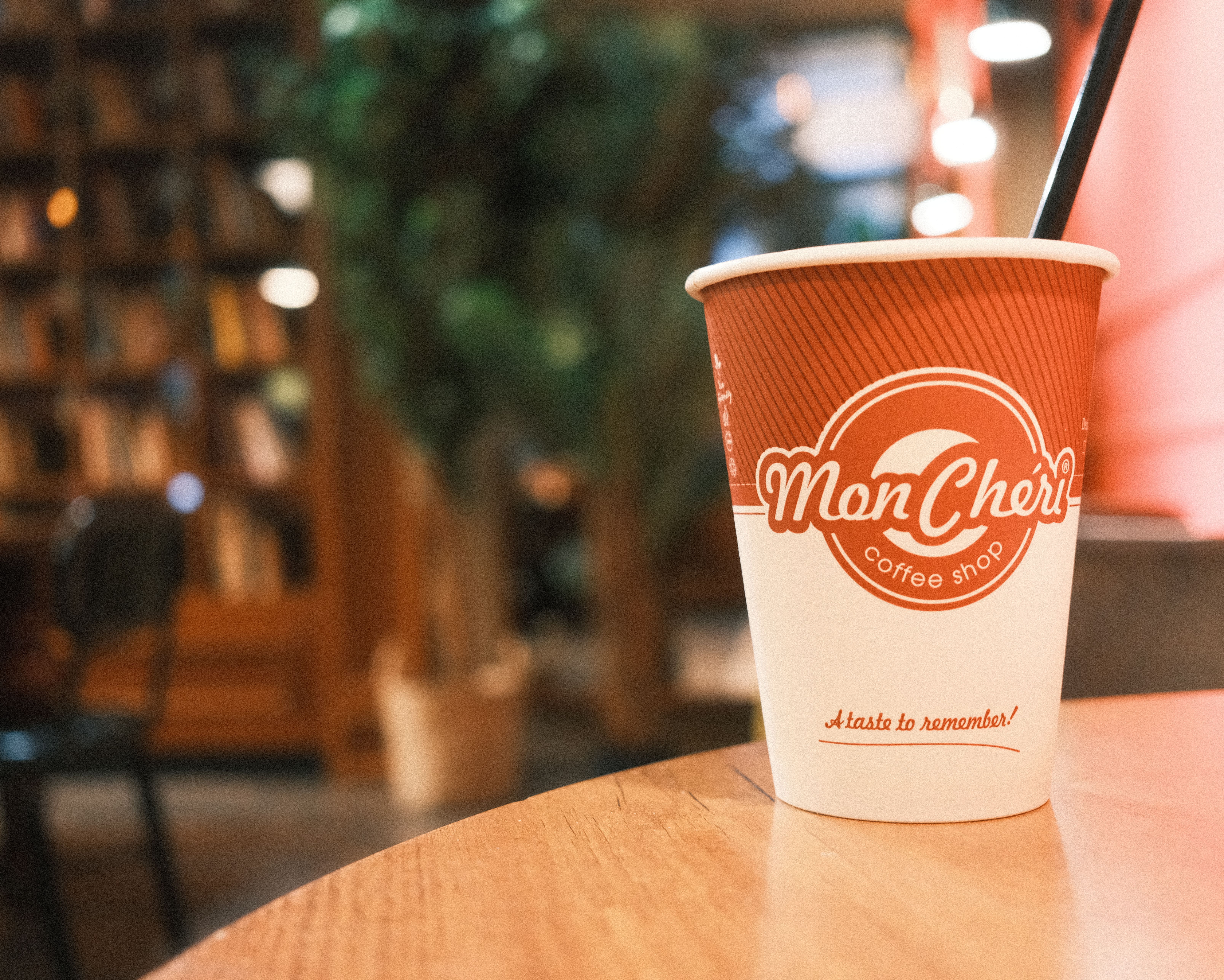 Warm ambiance in a Budapest coffee shop with a Mon Chéri takeaway cup on display.