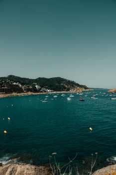 A picturesque summer view of Tossa de Mar's coastline with boats on the sea.