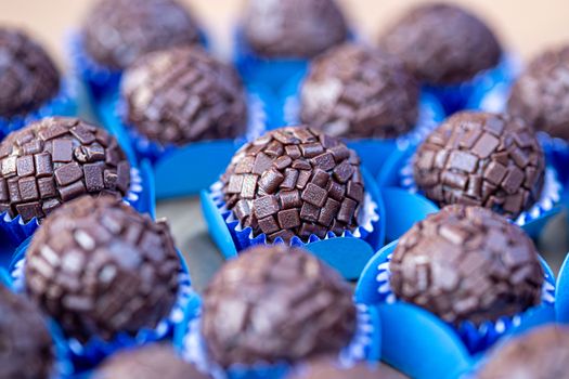 Close-up of chocolate brigadeiros with textured coating in blue liners, perfect for sweet indulgence.