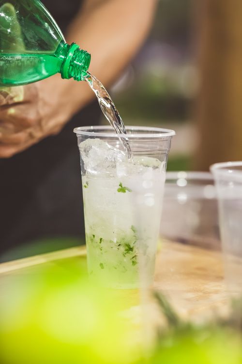 Free Close-up of a mojito being prepared with soda, ice, lime, and mint leaves. Stock Photo