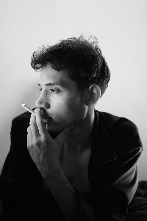 Free Black and white portrait of a man pensively smoking indoors. Stock Photo
