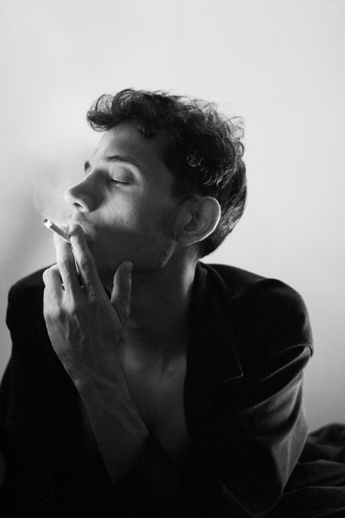 Free Black and white artistic portrait of a man smoking indoors. Stock Photo