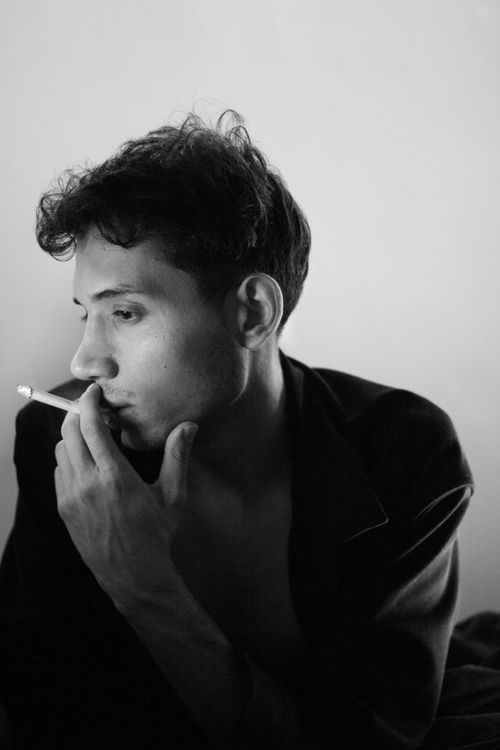Free Black and white portrait of a man smoking indoors with a thoughtful expression. Stock Photo