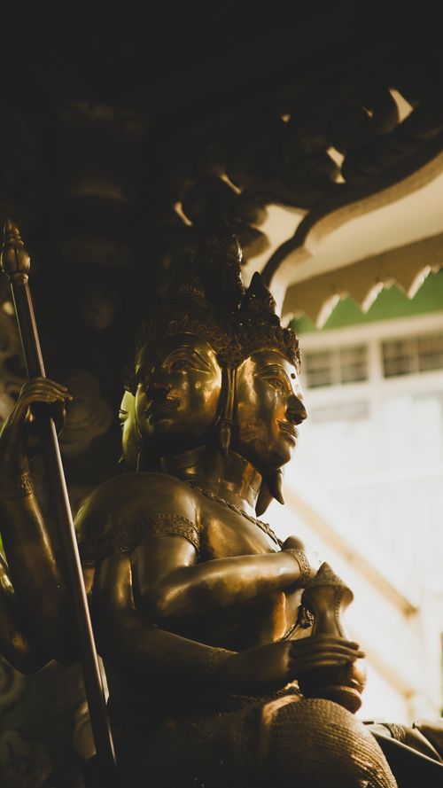 Free Close-up of a multi-faced golden Hindu deity statue in a Vietnamese temple setting. Stock Photo
